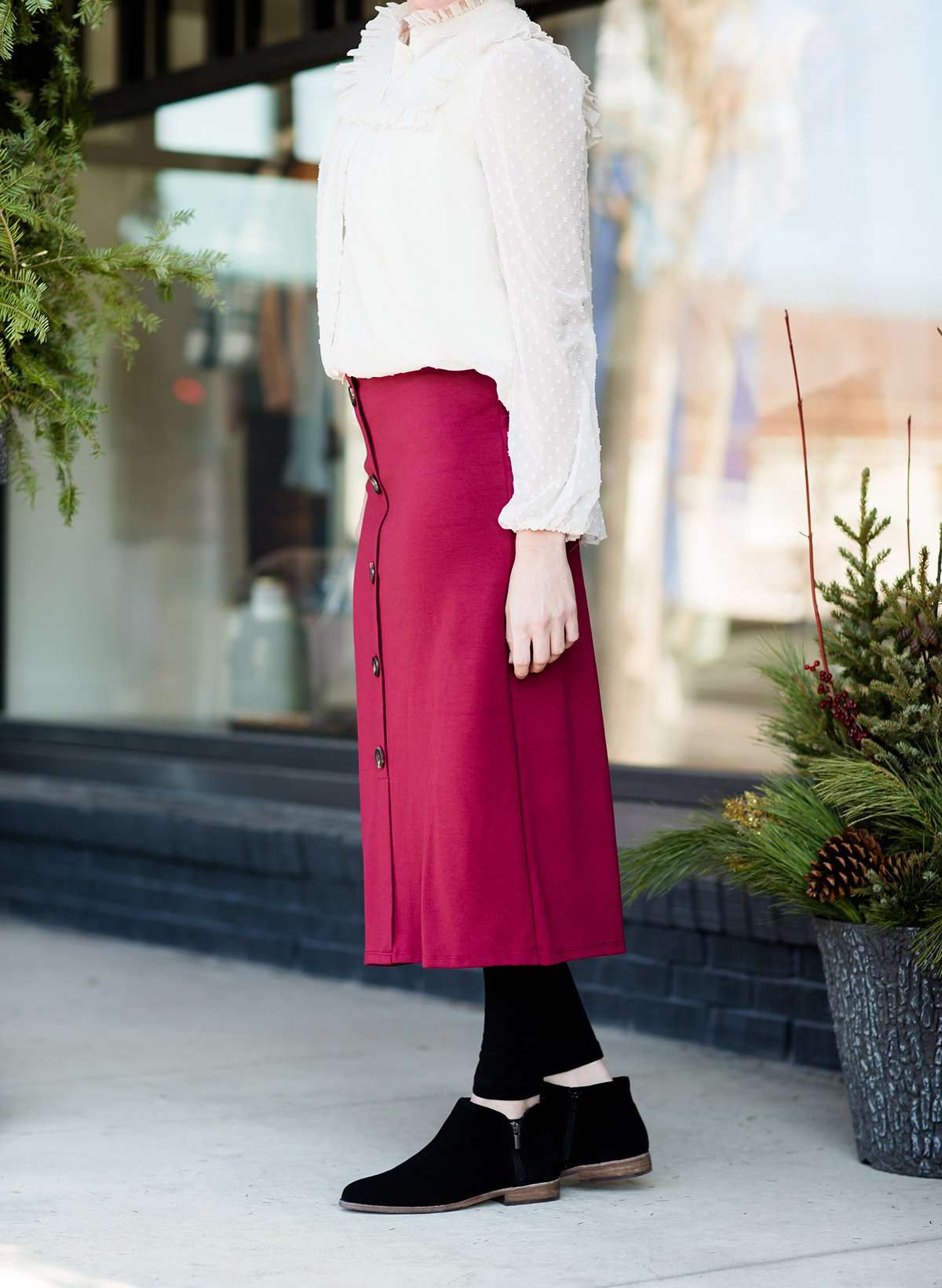 Modest below the knee wine colored skirt. This skirt has faux buttons and is paired with a white blouse and black boots.