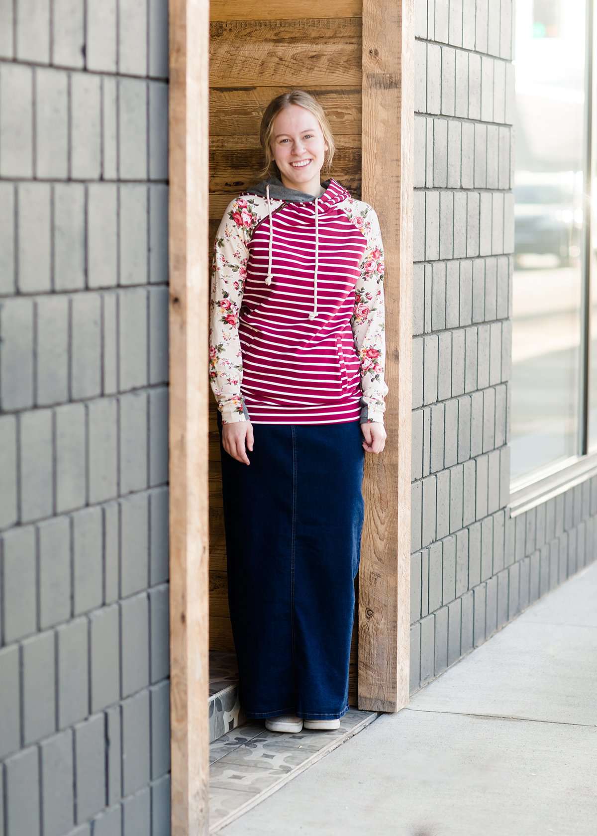 Woman wearing a long denim jean skirt that has a dark wash and a light wash. this is a long modest jean skirt.