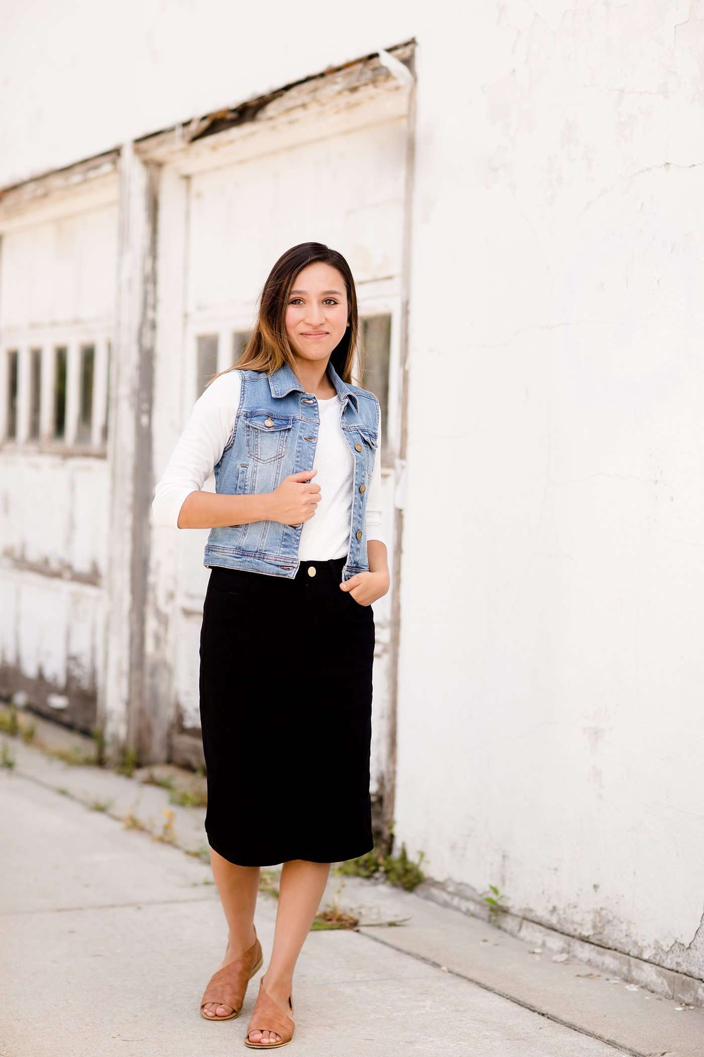 Woman wearing a black below the knee denim midi skirt.