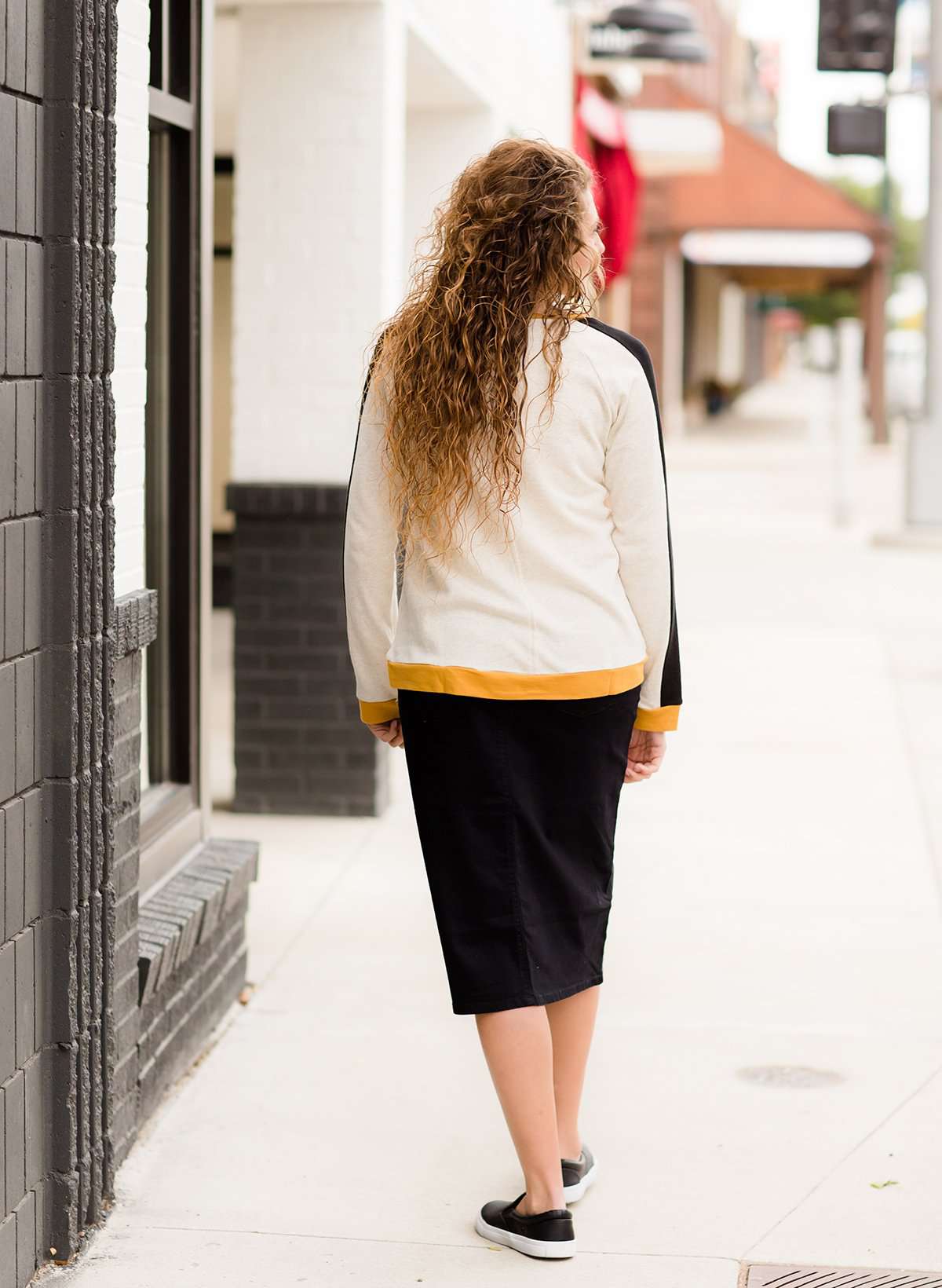 Woman wearing a black below the knee denim midi skirt.