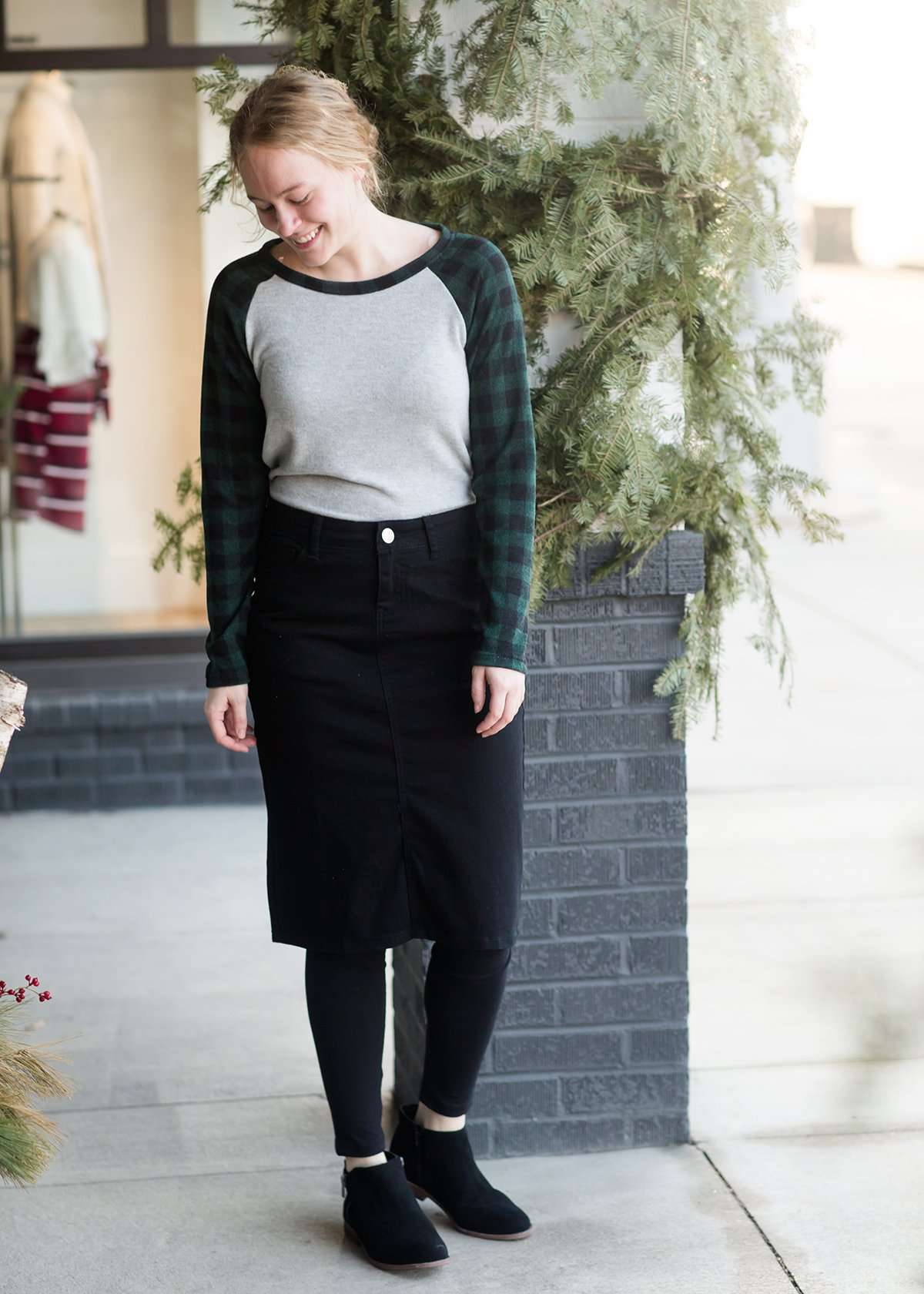 Woman wearing a black below the knee denim midi skirt.