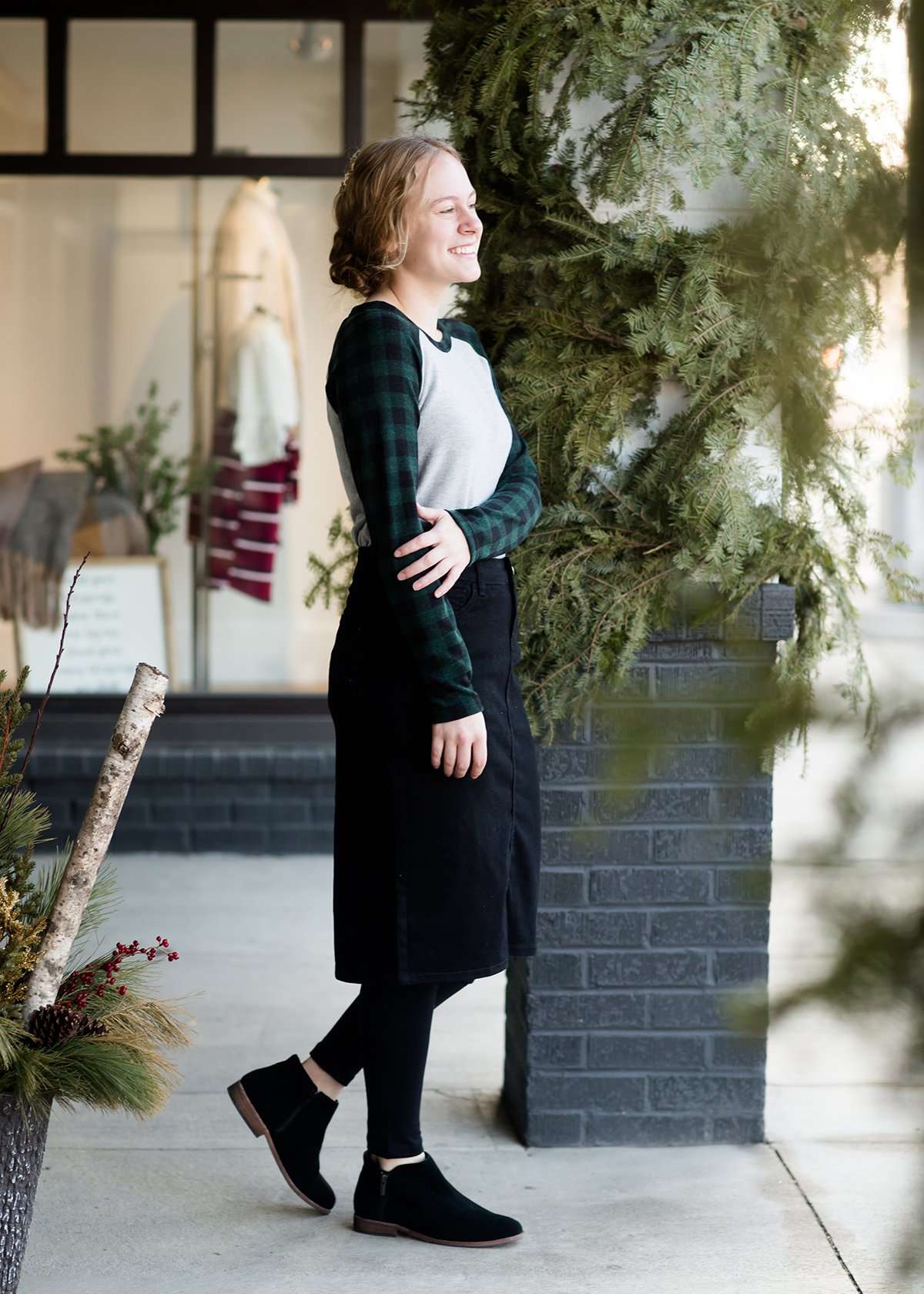 Woman wearing a black below the knee denim midi skirt.