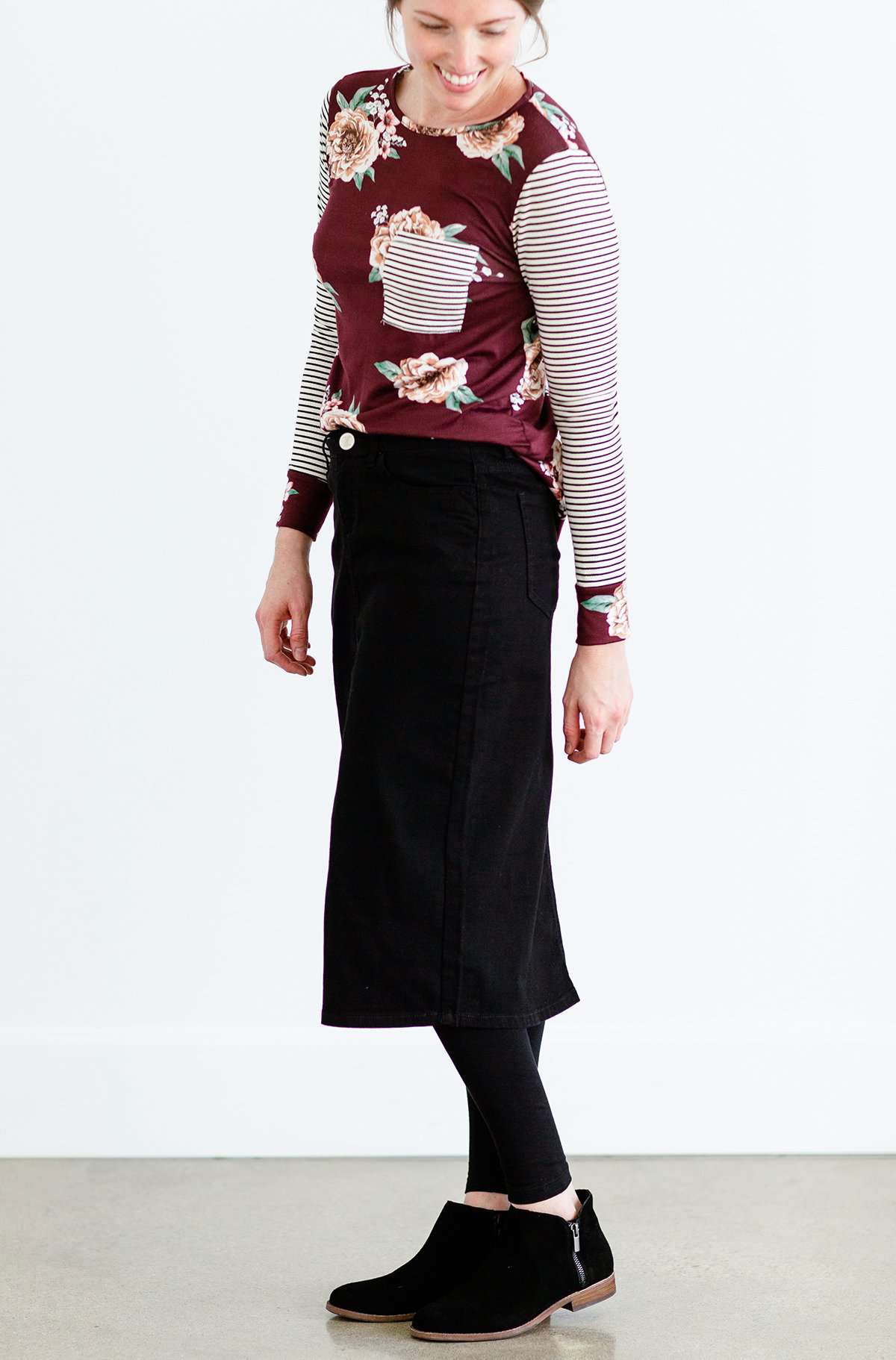 Woman wearing a black below the knee denim midi skirt.