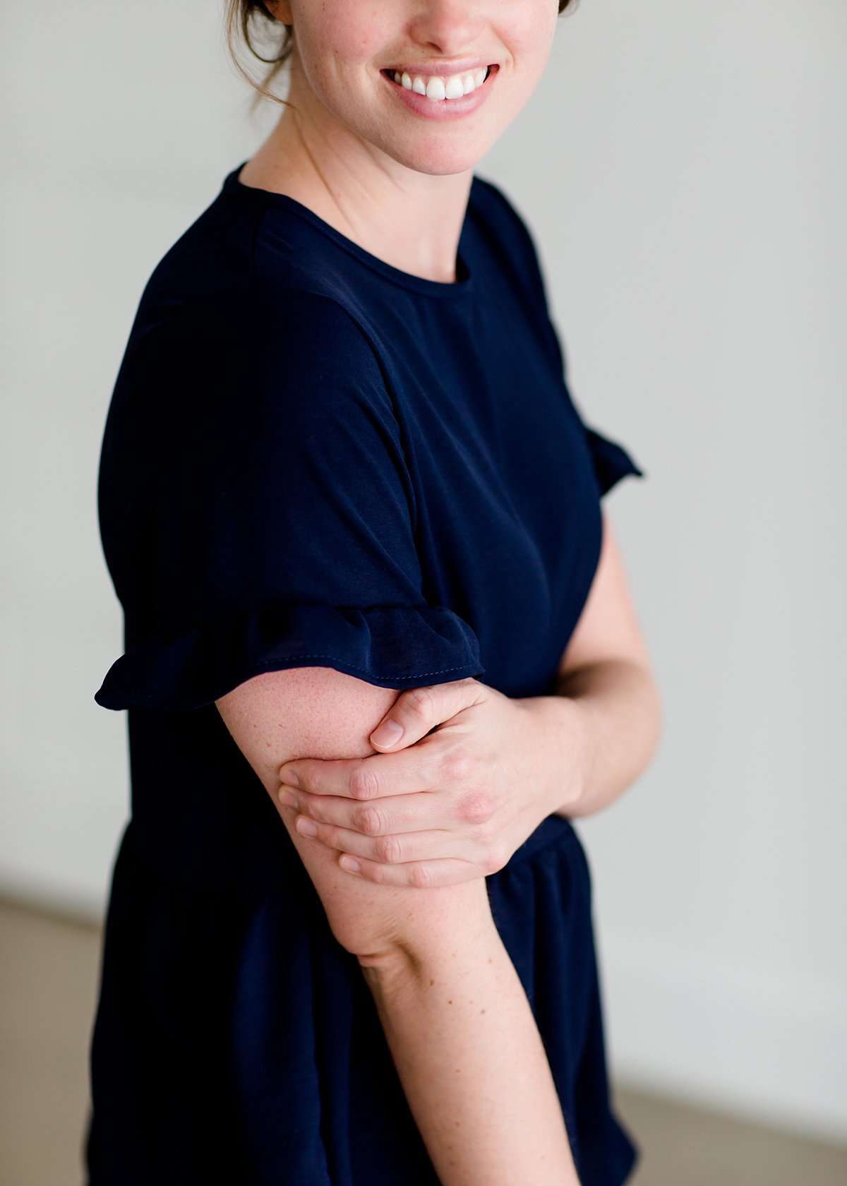 Woman wearing a navy peplum baby doll top that has ruffle details on the sleeves.
