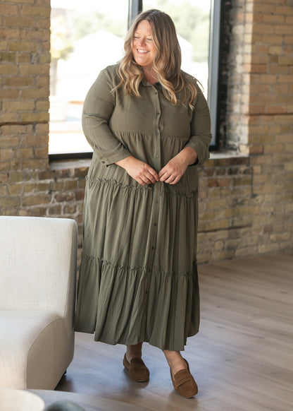 Olive button front midi dress styled with brown boots beside a chair.