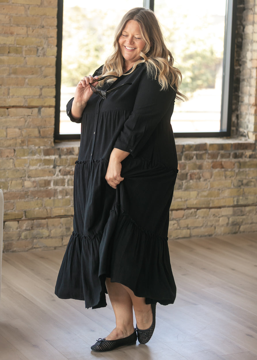 Black half sleeve midi dress in motion, showing the tiered skirt and calf-length hem.