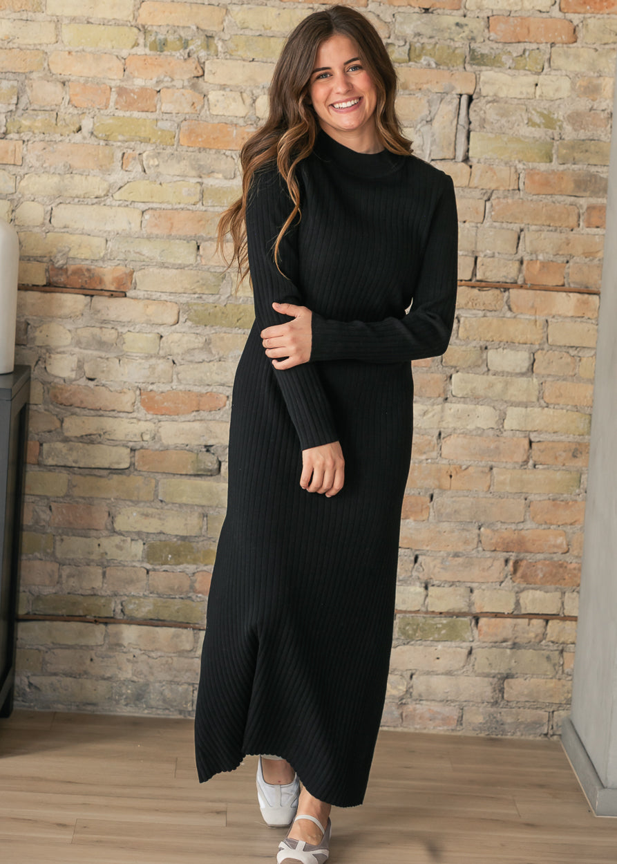 Black Ashdon maxi dress showing vertical ribbing and an ankle-length hem, modeled with one arm across the waist.