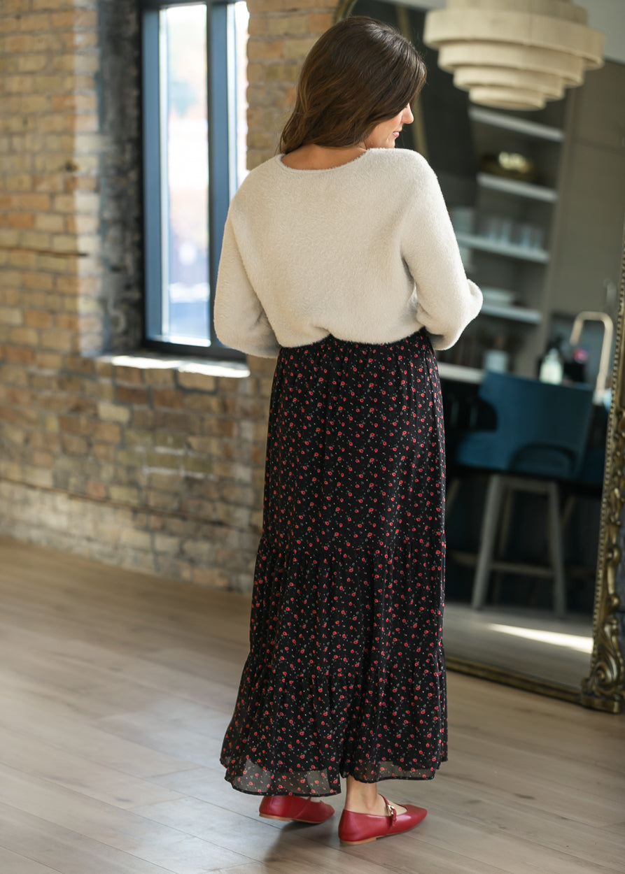Back of Lynn red floral tiered maxi skirt, styled with a cream cardigan and red Mary Jane flats.