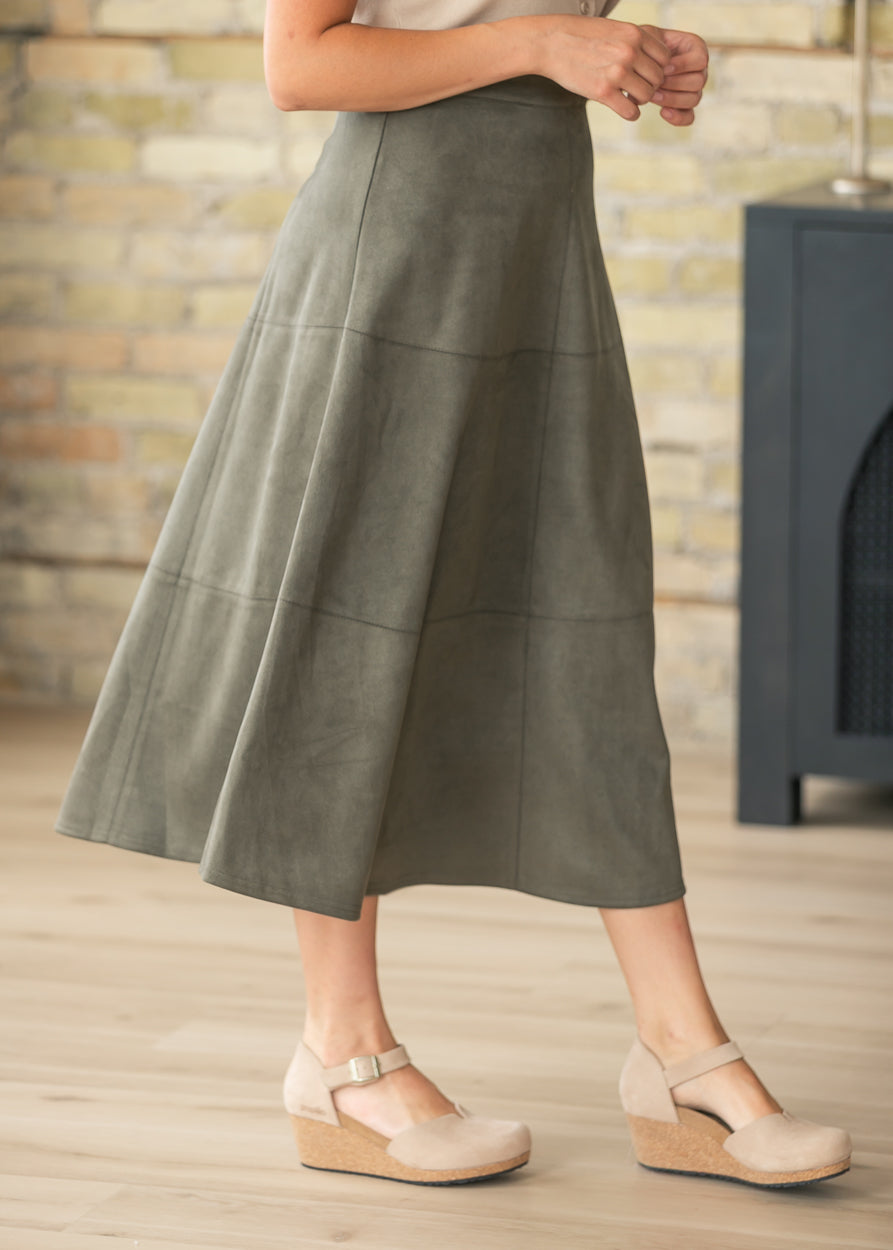 Close-up of olive faux suede midi skirt highlighting the paneled design and soft texture.
