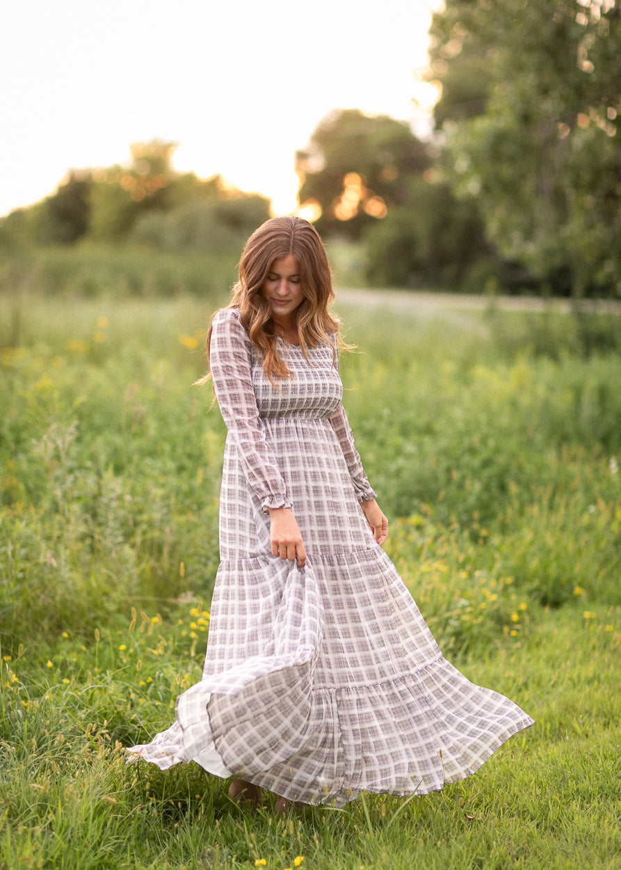 Taupe plaid maxi dress twirling to show the tiered, floor-length skirt in motion.