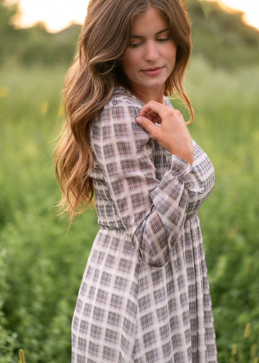 Close-up of the ruffled long sleeve cuff on the taupe plaid maxi dress in natural light.