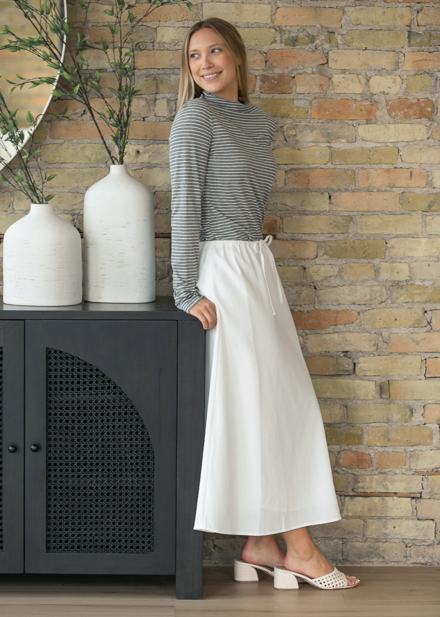 Soft ivory drawstring midi skirt with a straight silhouette and elastic waistband styled with a striped knit top.