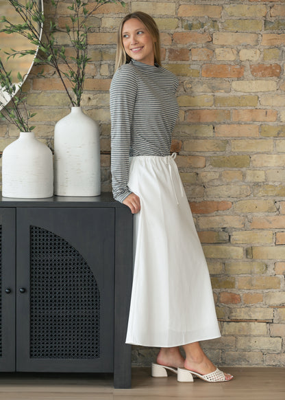 Soft ivory drawstring midi skirt with a straight silhouette and elastic waistband styled with a striped knit top.