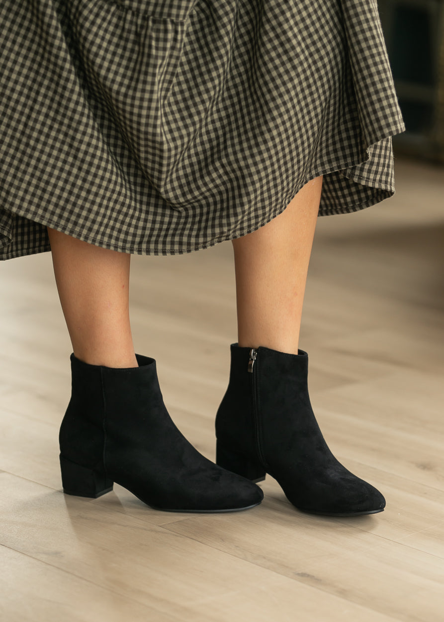 Black pointed toe ankle boots styled with a black gingham midi dress.