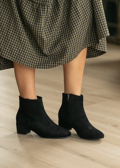 Black pointed toe ankle boots styled with a black gingham midi dress.