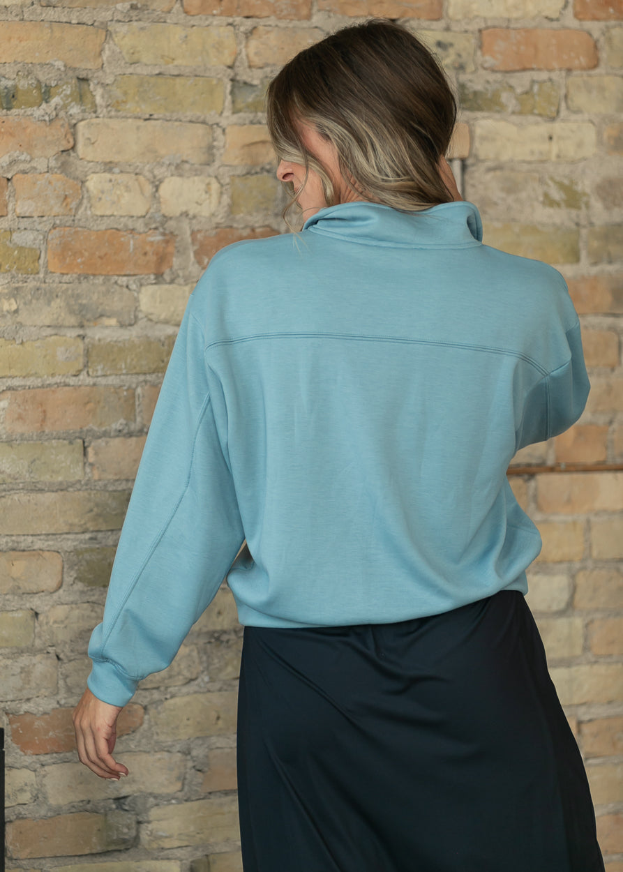 Back of blue-gray quarter-zip sweatshirt showing the yoke seam and ribbed hem.