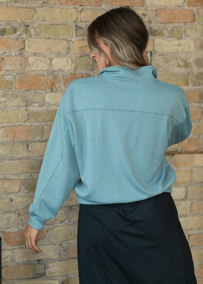 Back of blue-gray quarter-zip sweatshirt showing the yoke seam and ribbed hem.