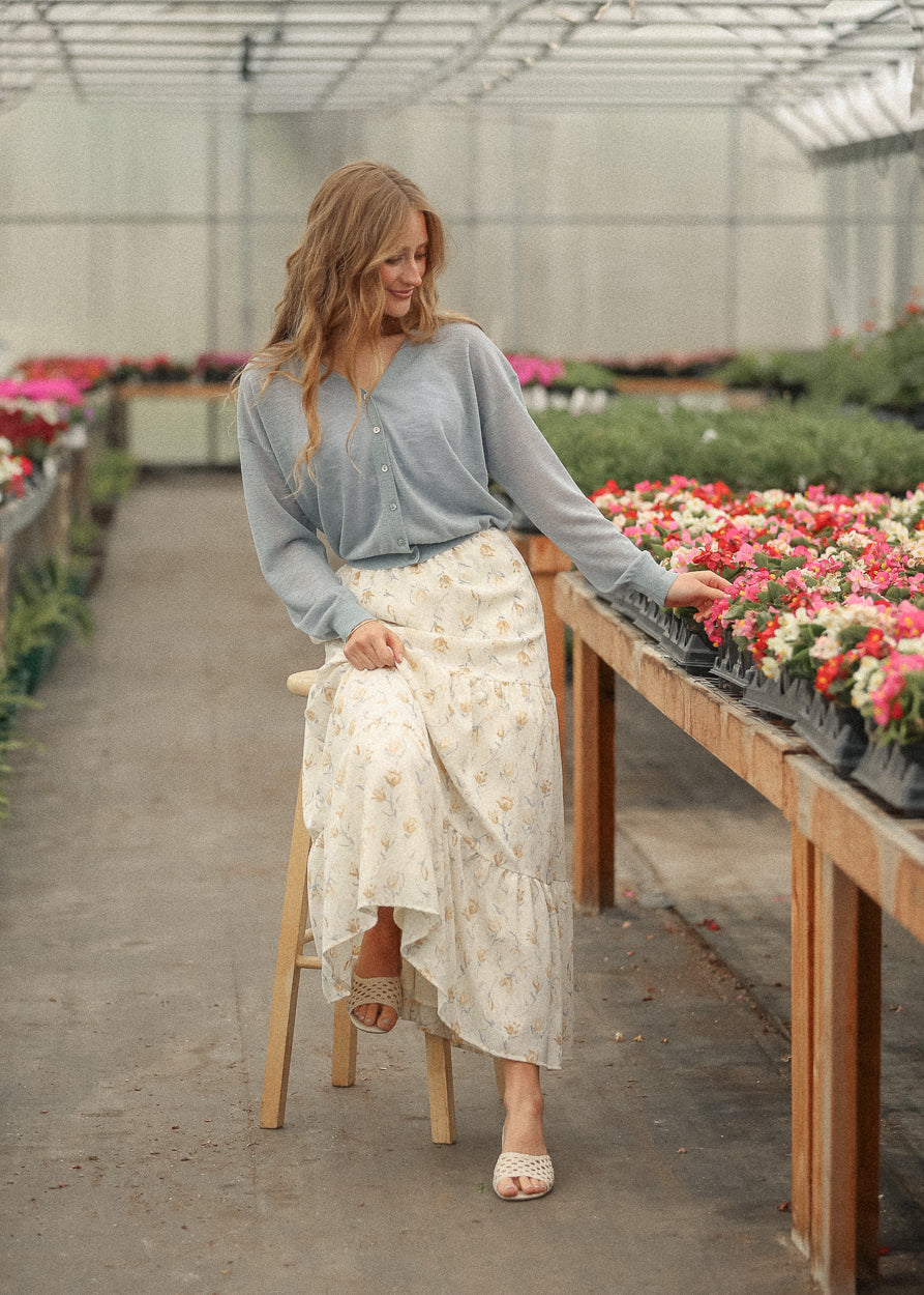 Blue lightweight v neck cardigan paired with a cream floral tiered skirt and woven heels