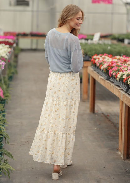 Back view of blue lightweight cardigan layered over a cream floral tiered maxi skirt