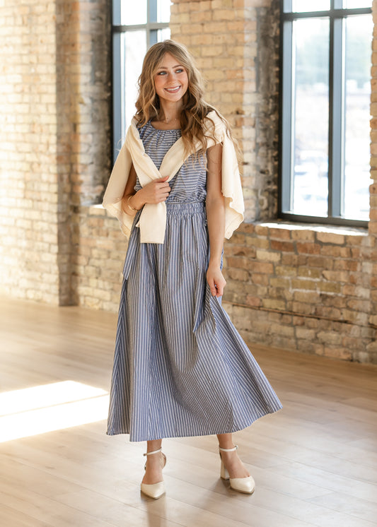 Blue and white striped two-piece top and maxi skirt set with cap sleeves, styled with cream heels and a cardigan.