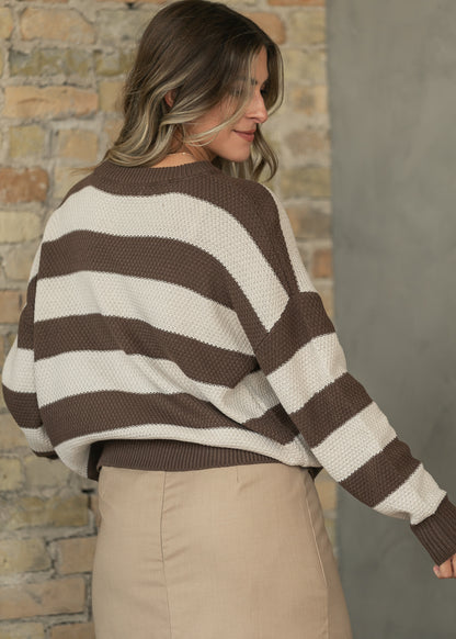 Back of brown and cream striped crewneck sweater showing ribbed hem and relaxed oversized shape.