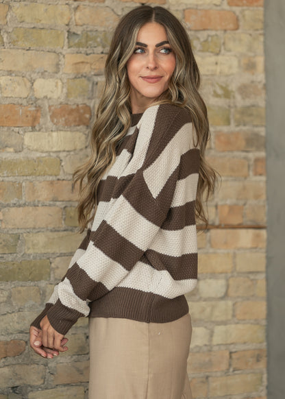 Close-up of the ribbed crewneck and brown and cream stripe pattern on the sweater's chunky knit.
