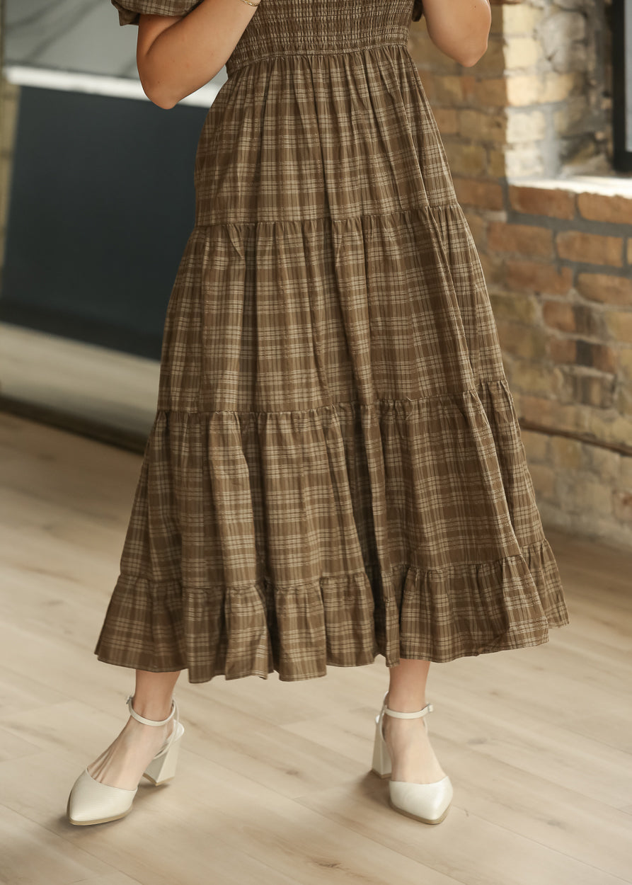 Close-up of brown plaid smocked bodice with square neckline and short puff sleeves.
