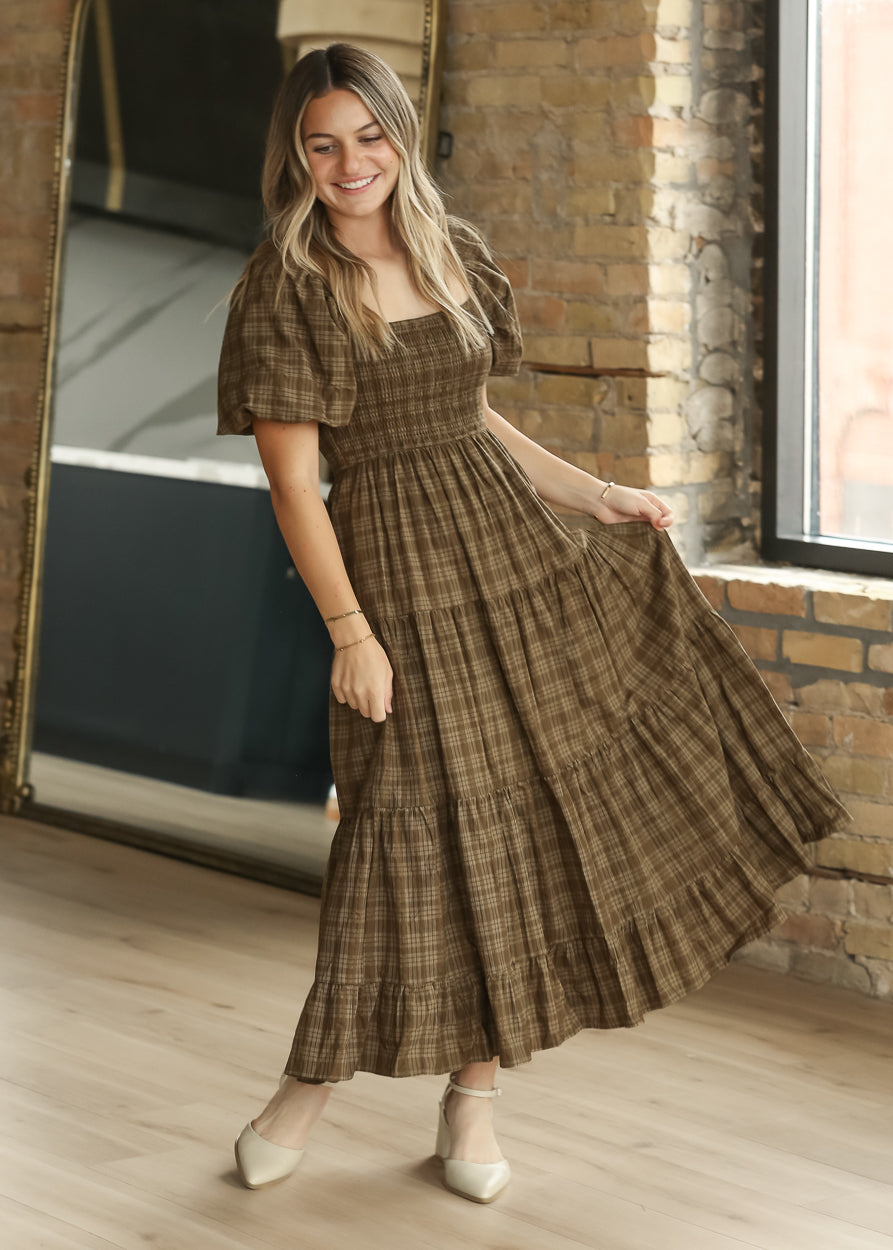 Brown plaid smocked midi dress in motion, showing the full tiered skirt and puff sleeve silhouette.