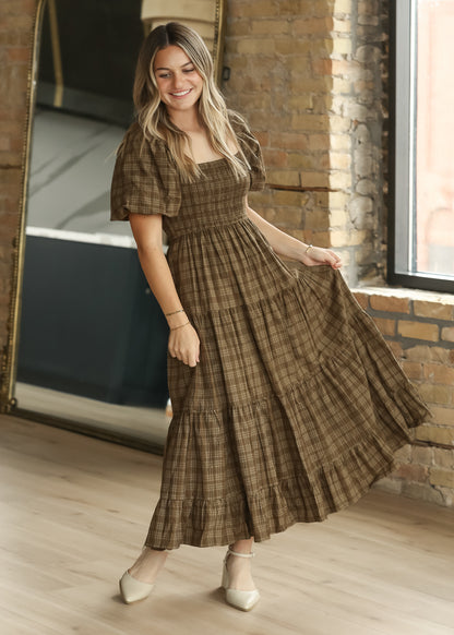 Brown plaid smocked midi dress in motion, showing the full tiered skirt and puff sleeve silhouette.