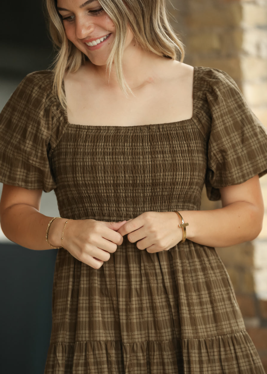 Brown plaid cotton midi dress styled with cream heels, showing the semi-fitted smocked bodice.