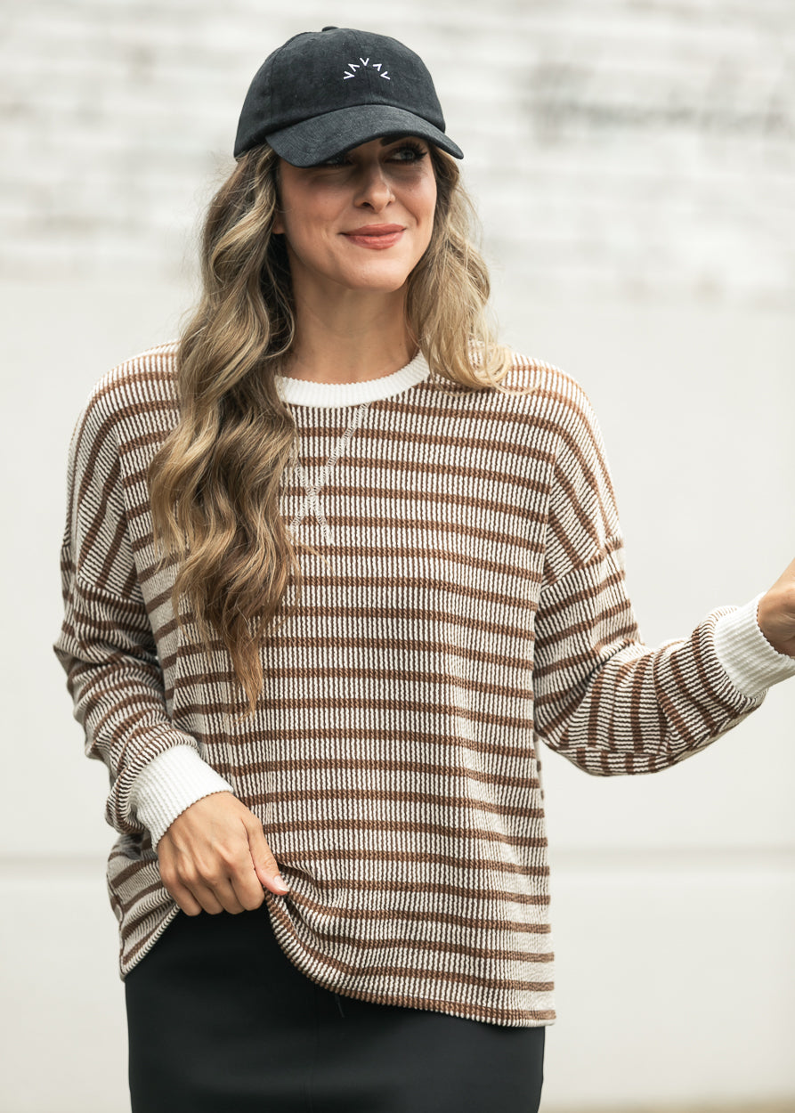 Close-up of brown ribbed round neck top with cream contrast trim and relaxed drop shoulders.