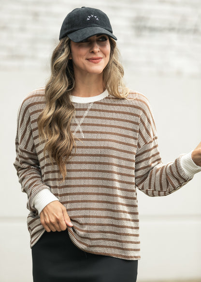 Close-up of brown ribbed round neck top with cream contrast trim and relaxed drop shoulders.