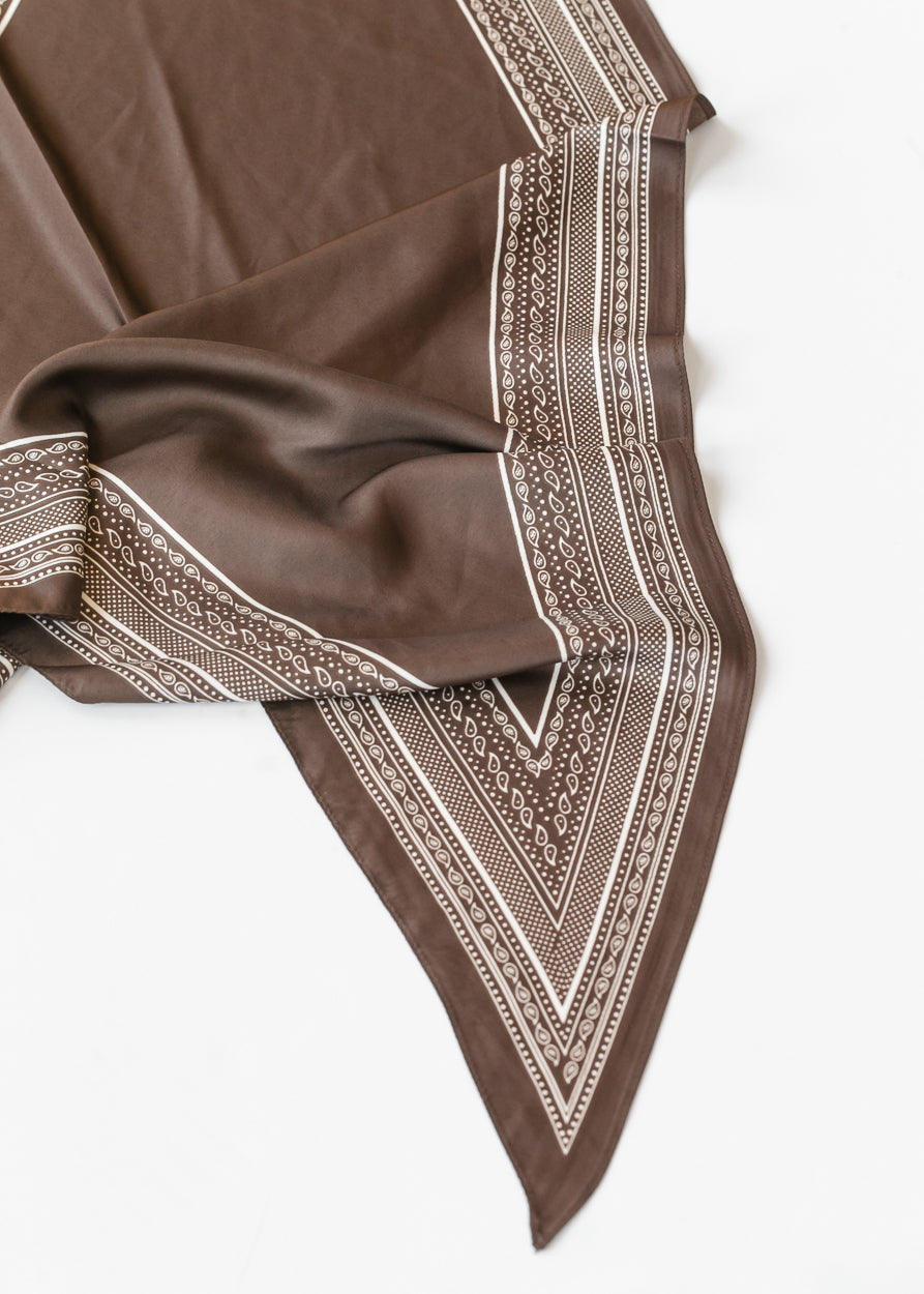Brown triangle scarf with cream border print, showing the pointed shape and smooth silk-cotton fabric.
