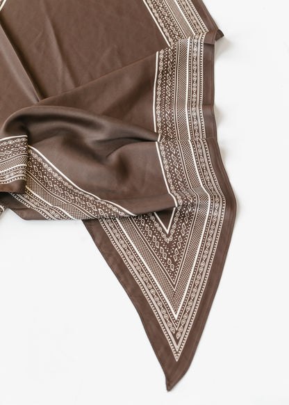 Brown triangle scarf with cream border print, showing the pointed shape and smooth silk-cotton fabric.