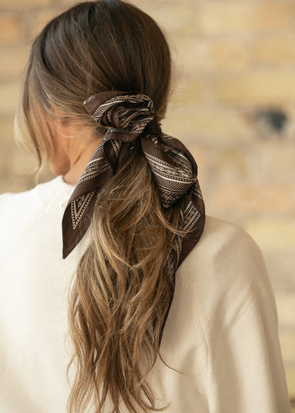 Brown triangle scarf with cream border print, showing the pointed shape and smooth silk-cotton fabric.