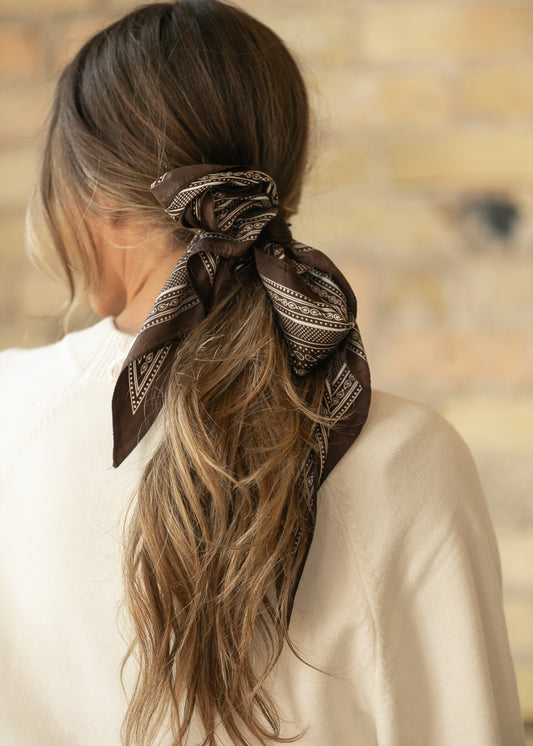 Brown triangle scarf with cream border print, showing the pointed shape and smooth silk-cotton fabric.