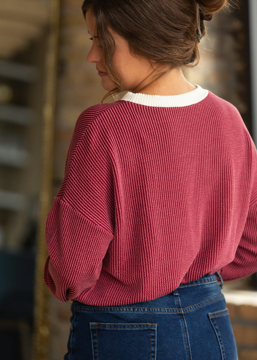 Back detail of burgundy ribbed pullover showing drop shoulders and cream contrast neckline.
