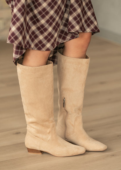 Close-up of camel faux suede tall boot with soft slouched shaft, side zipper, and low stacked heel.