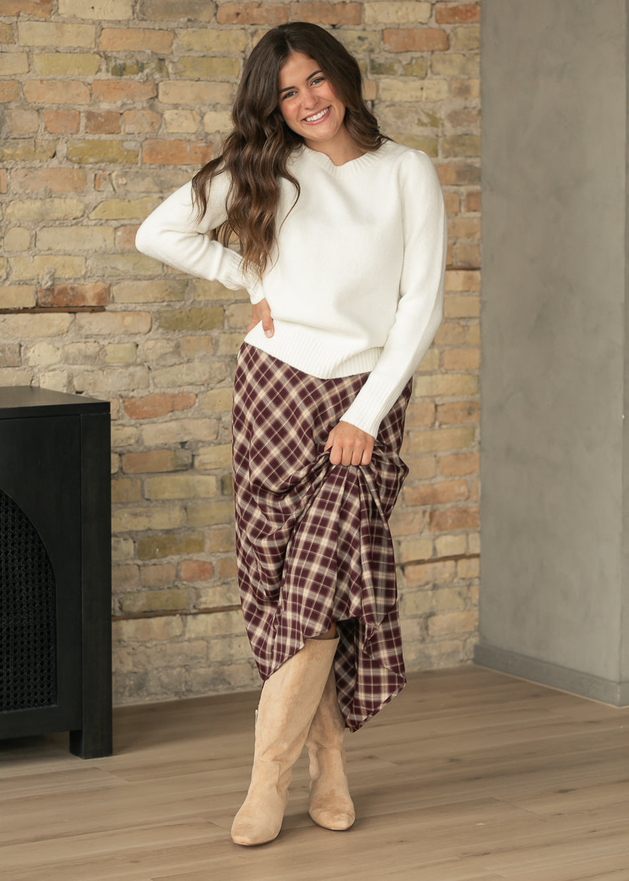 Burgundy and cream plaid A-line midi skirt styled with an ivory sweater and camel ankle boots.