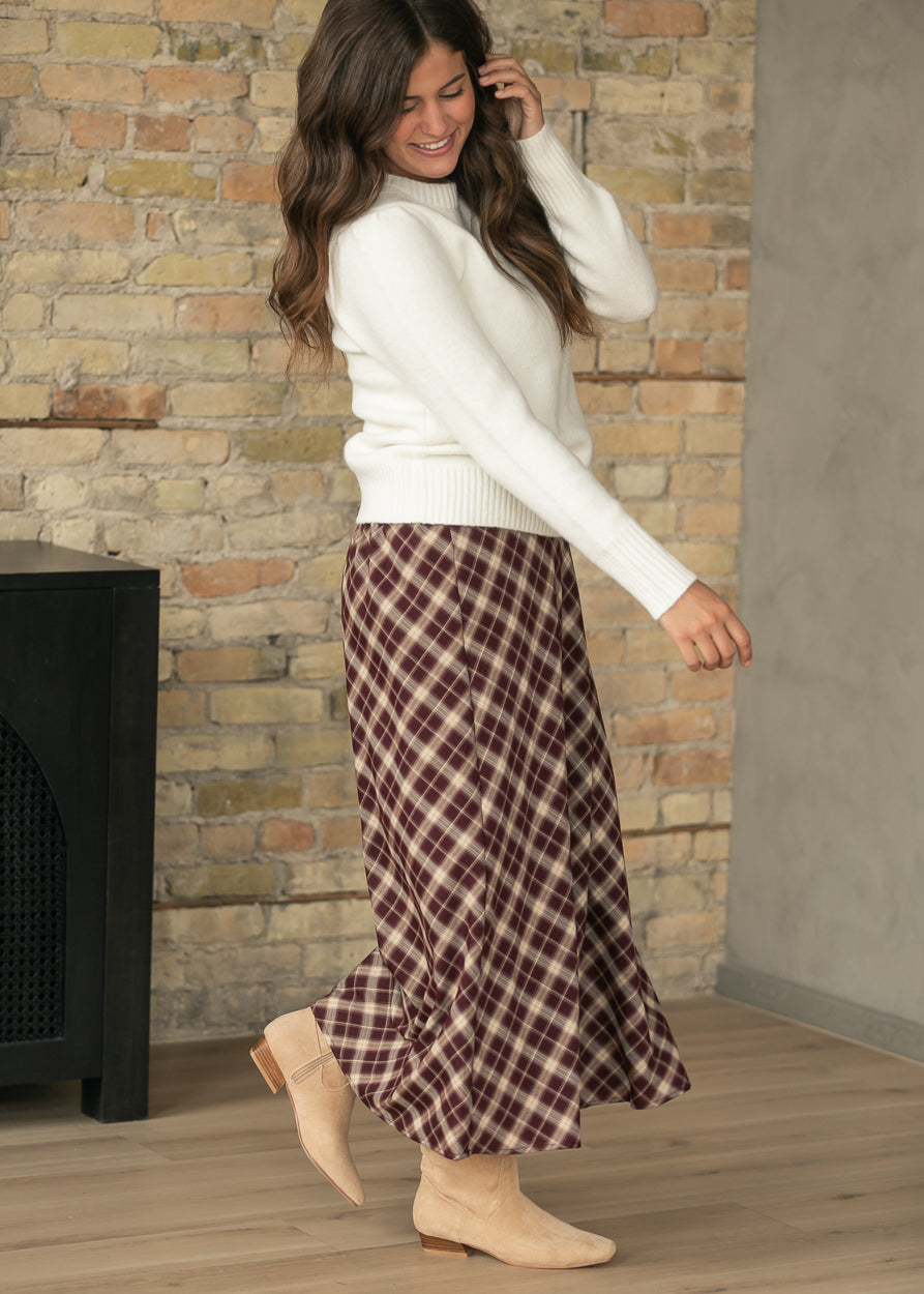 Flowing burgundy plaid midi skirt with A-line silhouette, styled with an ivory crew neck sweater.
