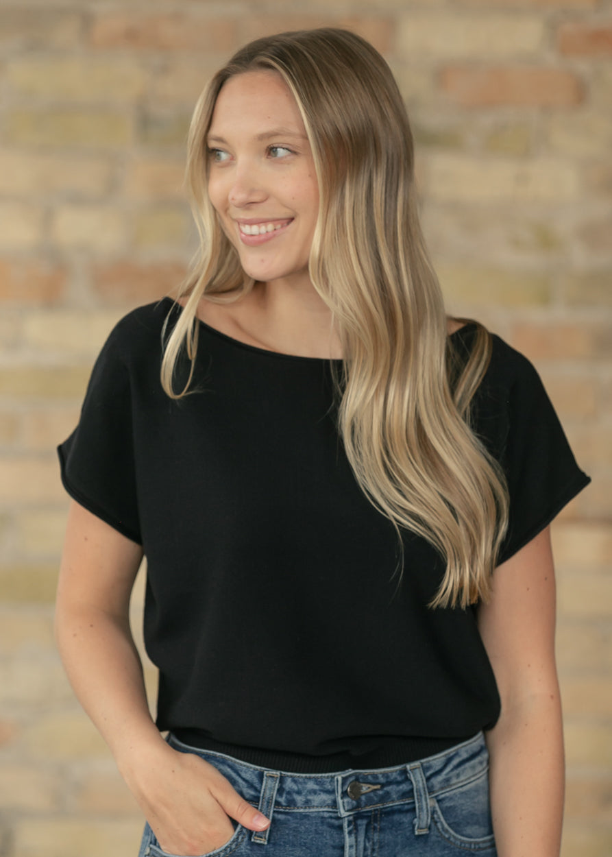 Close-up of black boat neck knit top with relaxed cap sleeves and soft drape.