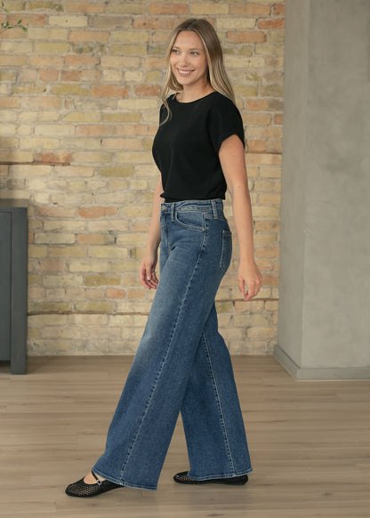 Black waist-length knit top paired with wide leg denim for everyday wear.