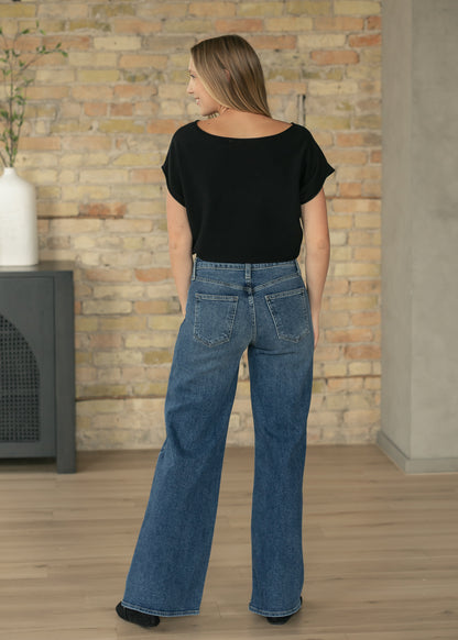 Rear detail of black cap sleeve knit top with waist-length fit.