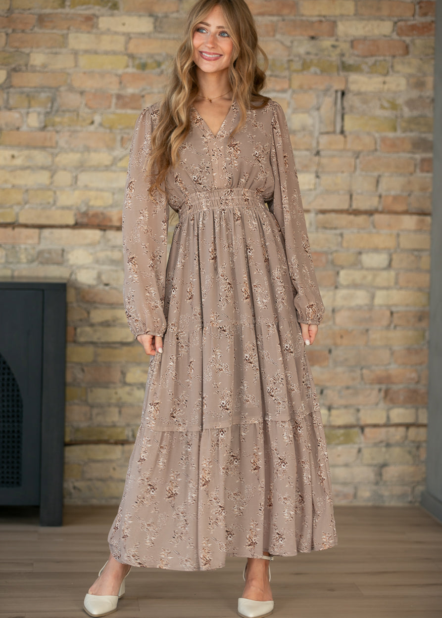 Celia brown floral maxi dress with V-neck, long sleeves, smocked waist, and tiered ankle-length skirt.