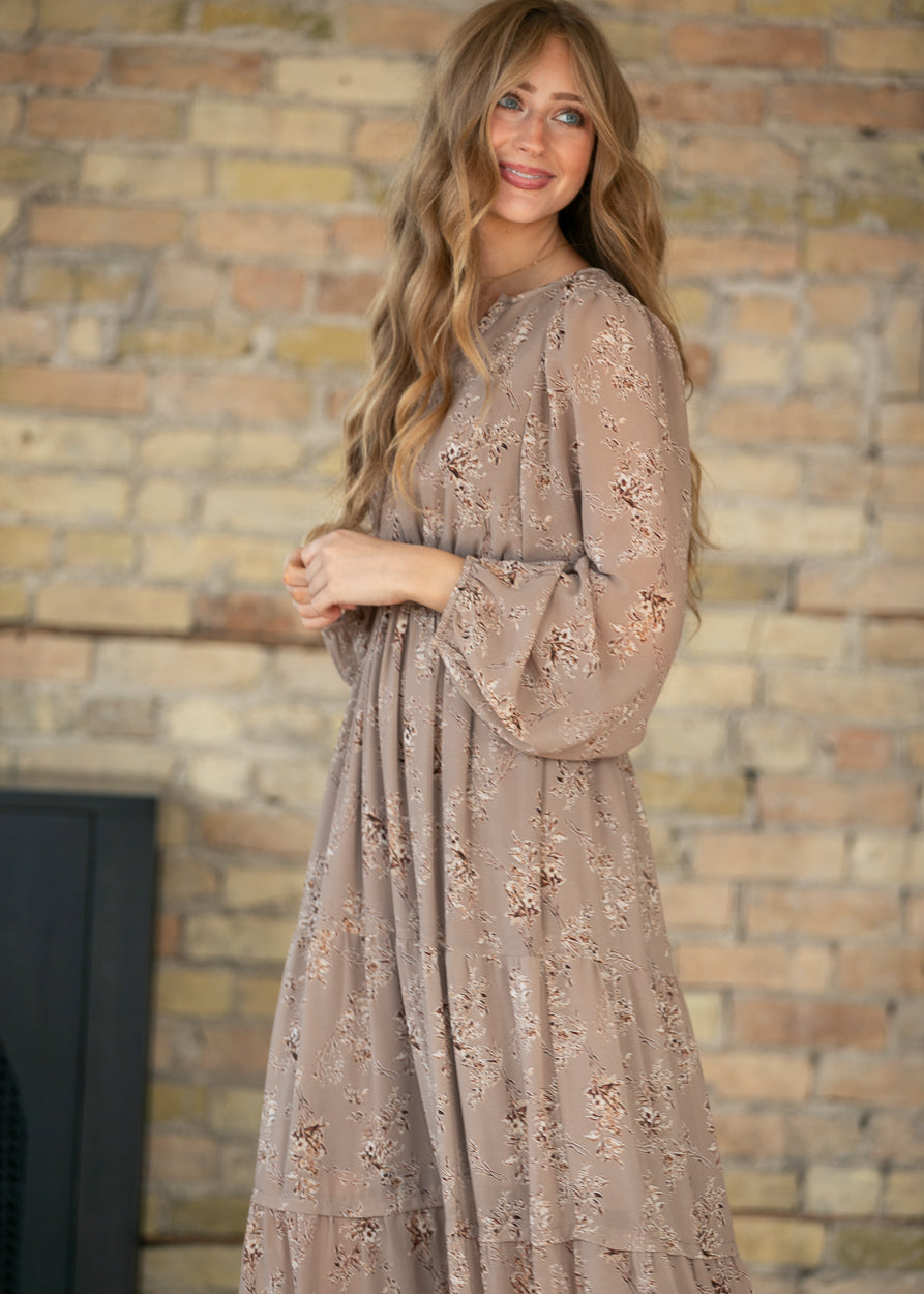 Side view of brown floral maxi dress showing the long sleeve shape and gathered waist.