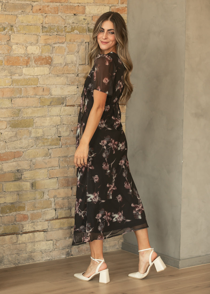 Side view of charcoal floral maxi dress with short sheer sleeves, fitted waist, and cream block heels.