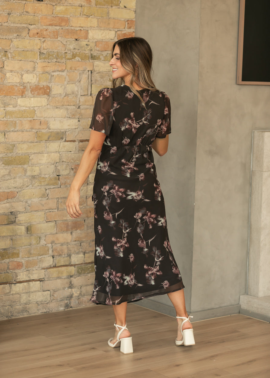 Back of charcoal floral maxi dress showing semi-fitted waist, short sheer sleeves, and ankle-length hem.