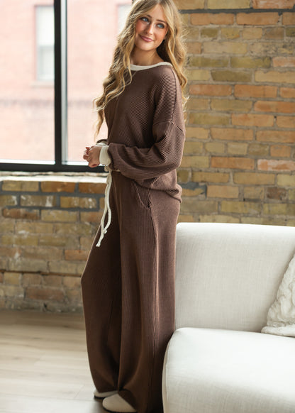 Side view of chocolate wide-leg ribbed pants showing full-length drape and relaxed leg shape.