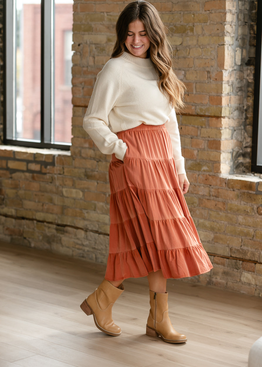 Two-tone rust tiered midi skirt styled with an ivory sweater and tan ankle boots.