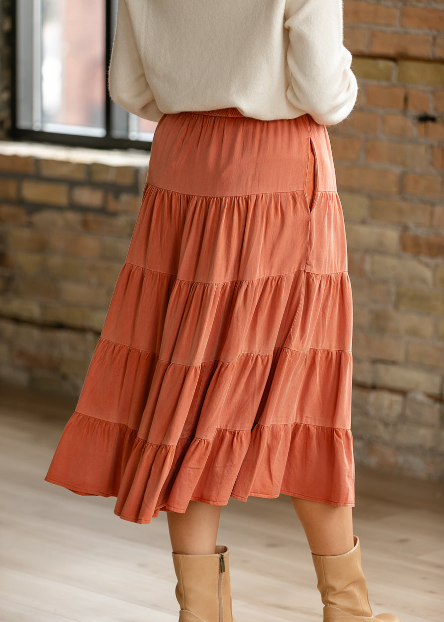 Two-tone rust washed tiered midi skirt shown from the back with an ivory sweater and tan boots.